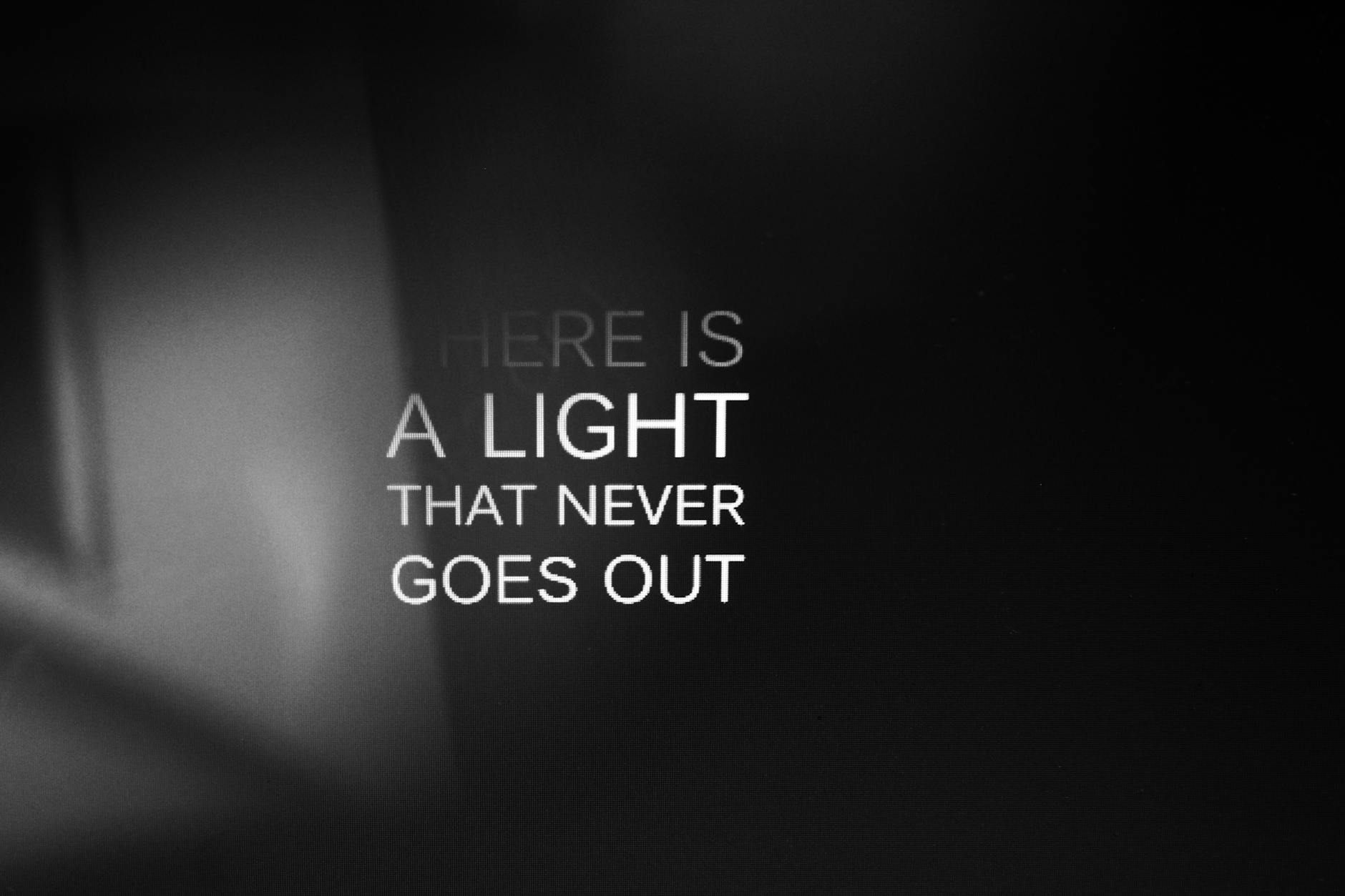 Shadowy dark background with white text that says There Is A Light That Never Goes Out